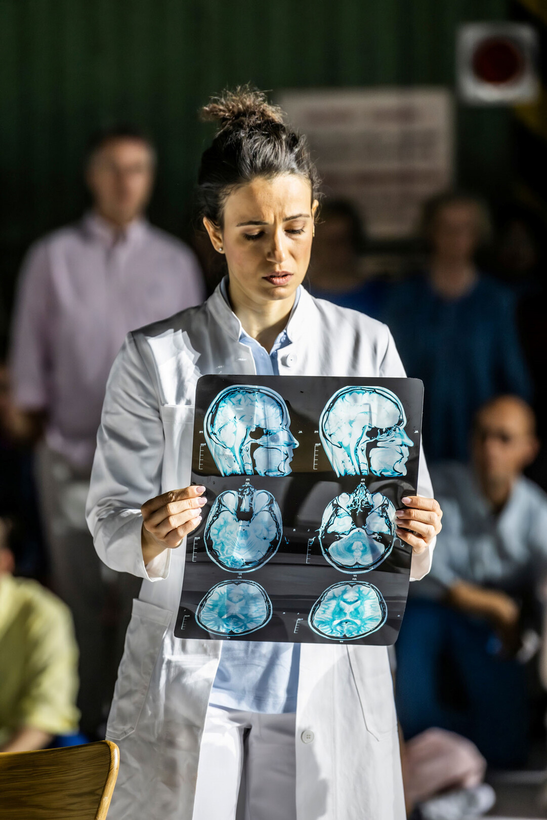 Frau hält Ausdruck eines MRT-Scans mit Querschnitten eines Kopfs in der Hand